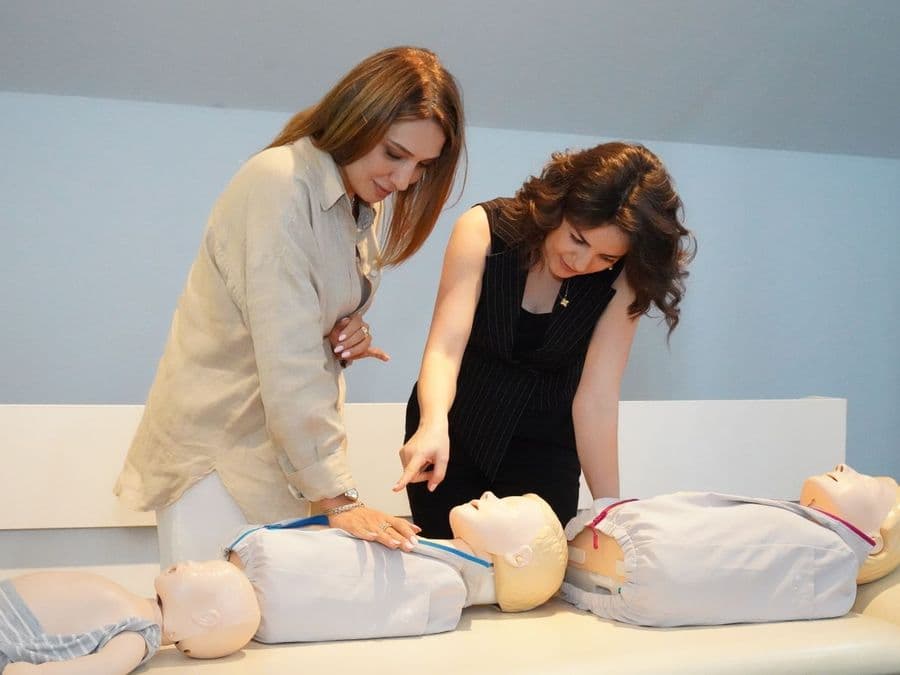 Two healthcare students practising chest compressions on manikins