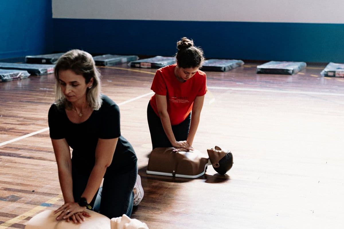 Two students practising BLS chest compressions on manikins during a class