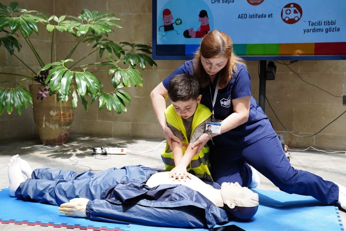 An instructor guiding a group through CPR practice on manikins