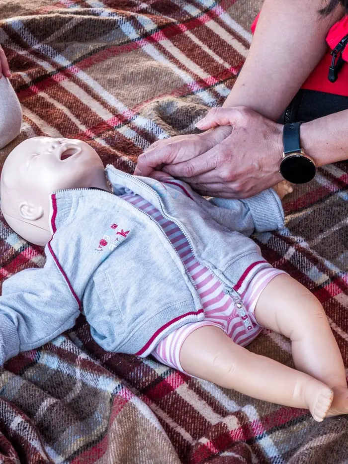 An instructor guiding a student through infant CPR on a training manikin